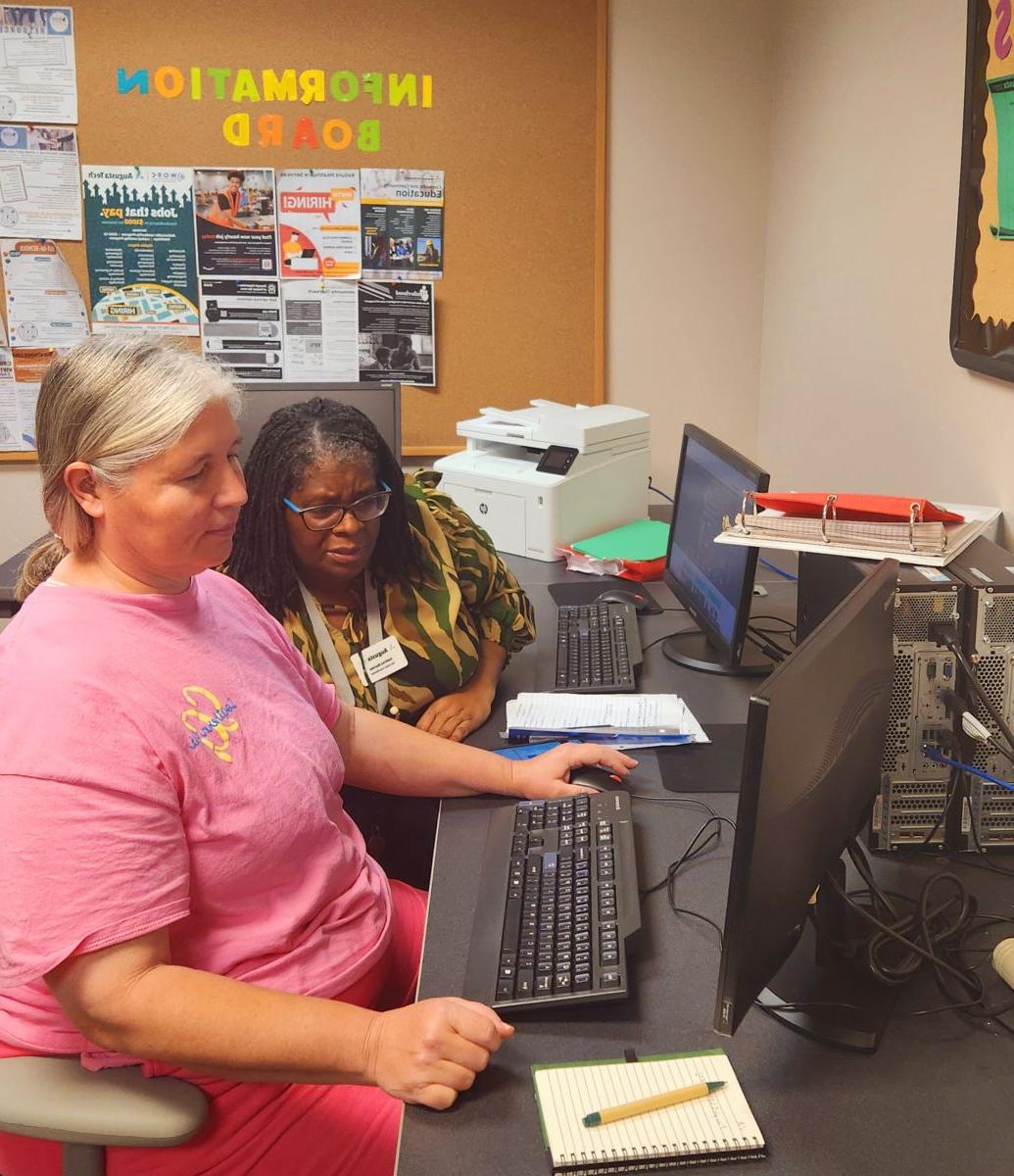 一站式服务的教职员工帮助正在使用电脑的学生.